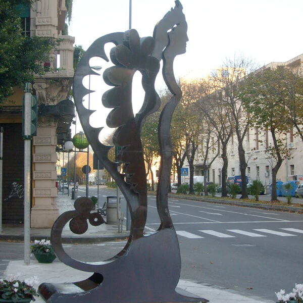 Il Passaggio dell'Angelo: a tall steel silhouette of a winged angel in profile, standing on a tree-lined city street in Messina.