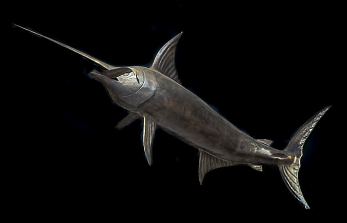 Forged iron swordfish at a three-quarter angle, bill raised and body arching as if mid-turn.