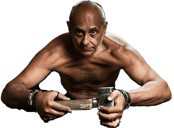 Fabio Pilato, bare-chested and leaning forward, holding a blacksmith&rsquo;s hammer in both hands and looking straight at the camera.